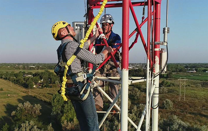 Federal Communications Commission Commissioner Brendan Carr, center, examines the installation of high-speed internet equipment Thursday on Midco's 330-foot telecommunications tower in Mitchell. Also pictured in the rear is Matt Hollingshead, of Midco. (Photo courtesy of Midco)