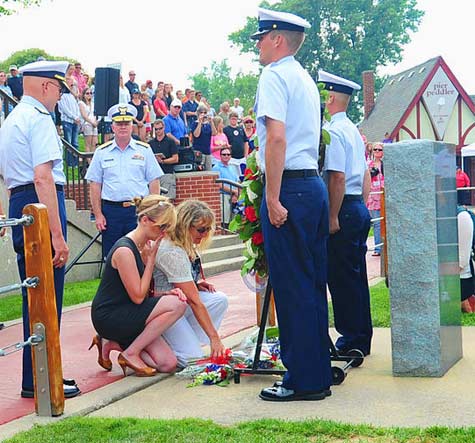 Amy and Nicola Belisle place a floral arrangement under the ceremonial wreath in honor of their fallen father and husband, retired U.S. Coast Guard Chief Boatswains Mate Richard Belisle, during the annual Coast Guard Festival's National Memorial Service, at Escanaba Park in Grand Haven, Mich., Aug. 2, 2013. Richard Belisle and Petty Officer 1st Class James Hopkins were murdered shortly after arriving for work at Coast Guard Air Station Kodiak, Alaska in April 2012.