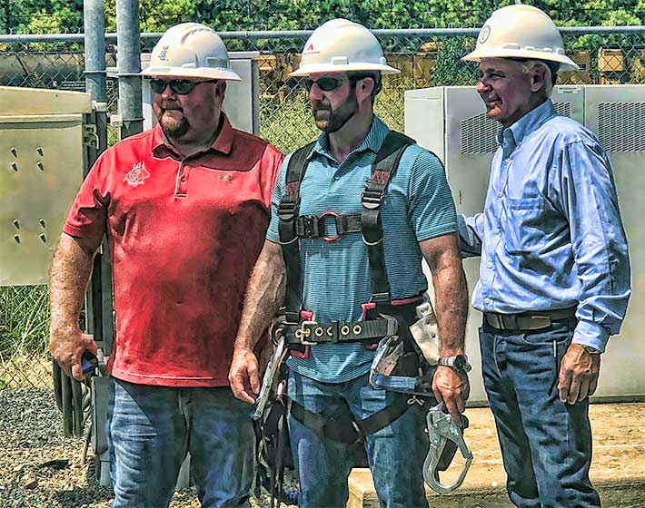 FIT AND GETTING FITTED UP FOR CLIMBING -- Jimmy Harbin of EasTex Tower, LLC, (left) along with Randy Scott, a member of the NATE Board of Directors From Texoma Contracting, Inc., set Congressman Markwayne Mullin up with a climbing harness. Mullin was given a cook's tour of an American Tower self-supporting structure in his Oklahoma Congressional District. Mullin, a former professional martial arts fighter, is battling to bring broadband to rural America.