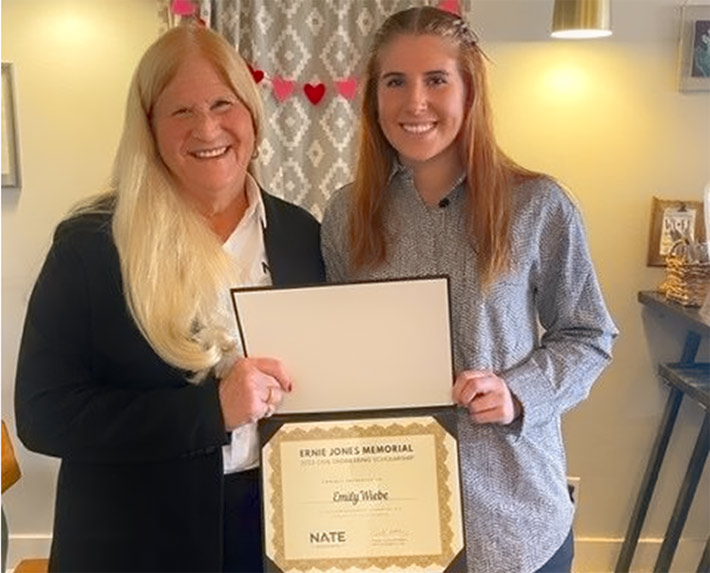 NATE Director of Safety, Health & Compliance Kathy Stieler presents Emily Wiebe with a plaque recognizing her as the 2023 recipient of the Ernie Jones Memorial Civil Engineering Scholarship. 