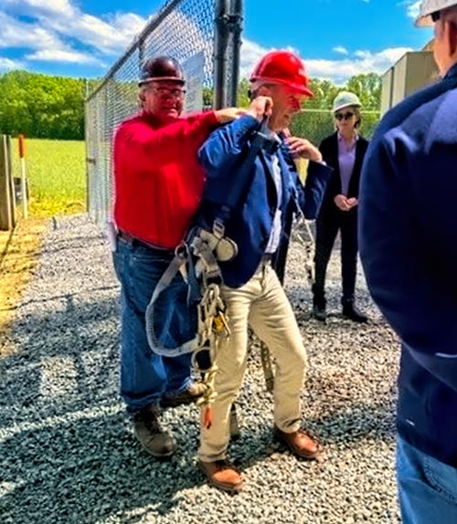 NATE Board of Director Kevin Dougherty of MILLENIA CONTRACTING, INC. assists Congressman Rob Wittman into a climbing harness during the Crown Castle site visit in Tappahannock, Virginia.